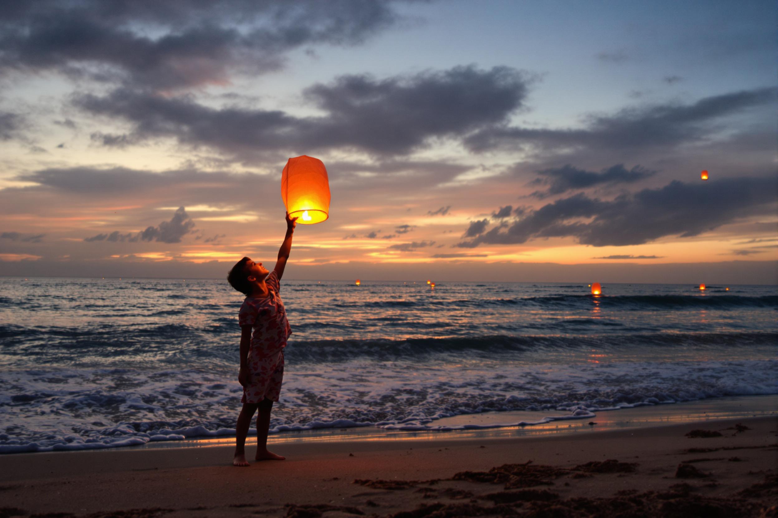 Child Releasing Lantern at Sunset Shoreline