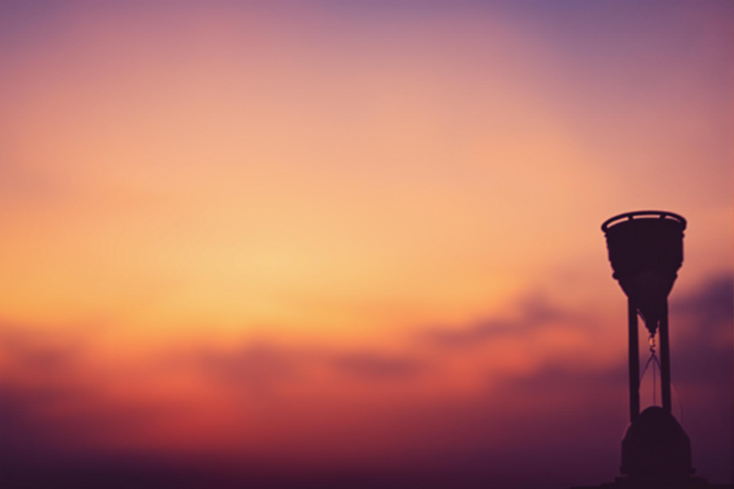 Minimalist Hourglass Silhouette Against Sunset Sky