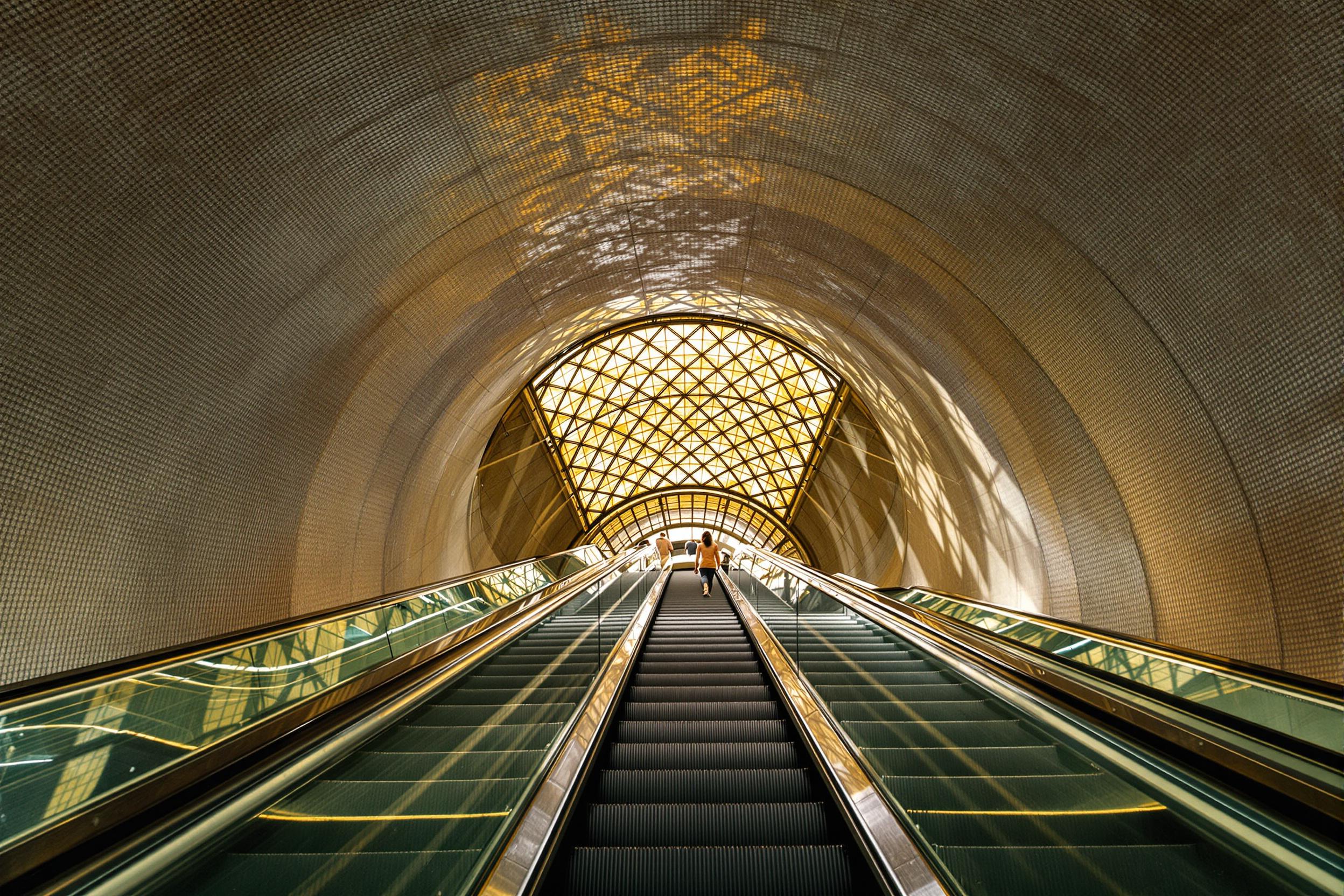 Golden-lit Subway Escalator in Geometric Atrium